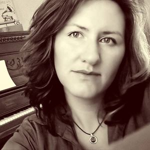 Elizabeth Matthews - black and white portrait in front of piano